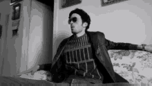 a black and white photo of a man sitting on a couch