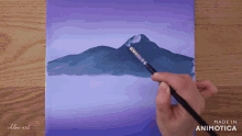a person is painting a mountain with a brush on a purple background made in animatica