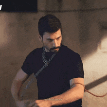 a man with a beard is wearing a black shirt and a chain around his wrist .