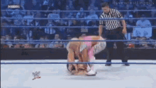two wrestlers are wrestling in a ring with a referee in the background