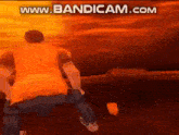 a man in a yellow shirt is standing in front of a fire .