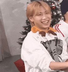 a man wearing a sweater with an elephant on it is smiling in front of a christmas tree