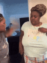 a woman wearing a shirt with the letter p on it is standing next to another woman in a room
