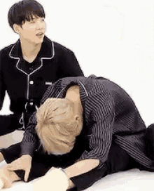 two young men are sitting on the floor one is laying down and the other is sitting up