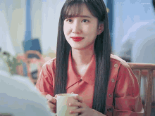 a woman in a red shirt is holding a cup of coffee