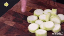 a bunch of sliced zucchini on a wooden cutting board with the words made in animotica on the bottom