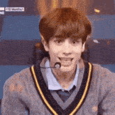 a young man is wearing a sweater and a microphone .