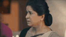 a woman in a saree is making a funny face while looking at something .