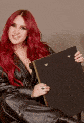 a woman with red hair is wearing a black leather jacket