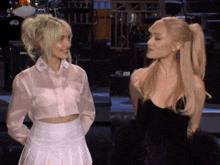 two women are standing next to each other on a stage and one is wearing a black dress