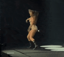 a woman is dancing on a stage with a microphone in her hand