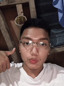 a young man wearing glasses is giving a thumbs up sign