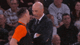a man in a suit talks to another man in an orange shirt