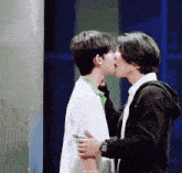 two young men are kissing each other on the cheek while standing next to each other .