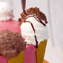a chocolate drizzle is being applied to a ice cream cone