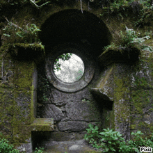 a stone wall with a round hole in the middle and pixiz written on the bottom right corner