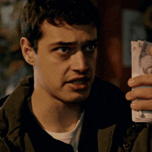 a man covering his face with a stack of 200 bills