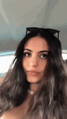 a woman with long dark hair is wearing sunglasses and a necklace .