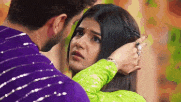 a man and a woman are looking at each other and the woman is touching the man 's head .