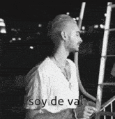 a black and white photo of a man standing next to a ladder with the words `` soy de val '' written on it .