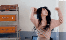 a woman is dancing in front of a shelf with suitcases