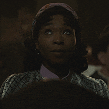 a woman wearing a headband and earrings looks at the camera