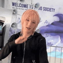 a person with pink hair is standing in front of a sign that says welcome to oxo society