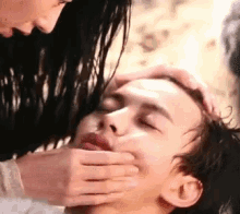 a woman is putting her hand on a man 's mouth .