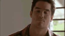 a man wearing a plaid shirt is making a funny face .