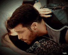 a woman with blue nails is touching a man 's hair with the name sophie written on the bottom