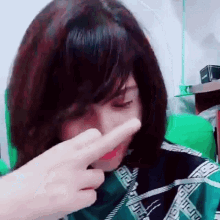 a woman wearing a wig is covering her nose with her hand .