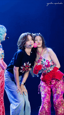 a woman blowing a pink bubble while standing next to two other women
