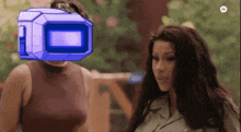 a woman standing next to another woman with a blue box on her head