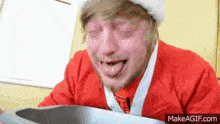 a man in a santa suit is making a funny face with his tongue hanging out .