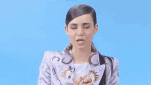 a woman wearing a purple jacket and a white dress is making a funny face