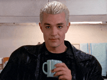 a man with a spike in his hair holds a cup of coffee