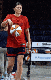 a woman in a red shirt that says ucs on it holds a basketball