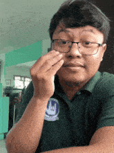 a man wearing glasses and a green shirt with a sign language symbol on the front