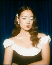 a woman wearing a black and white dress and earrings