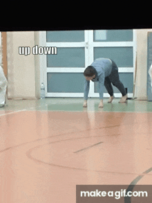a man is doing a handstand on a basketball court and the words up down are above him