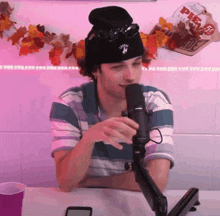 a man wearing a black beanie and sunglasses is talking into a microphone