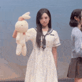 a girl in a sailor outfit holds a stuffed bunny