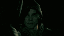 a woman in a hooded jacket is looking at another person in the dark