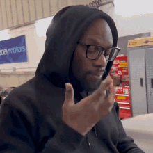 a man wearing a black hoodie and glasses is sitting in front of a sign that says ebaymotors .