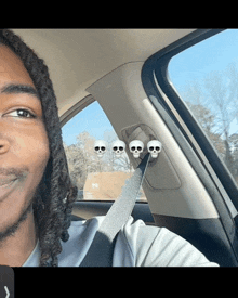 a man with dreadlocks is sitting in a car with three skulls on the side