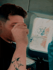 a man with a tattoo on his arm covers his face