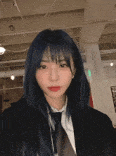 a girl with blue hair is wearing a black jacket and tie .