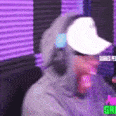 a man wearing headphones and a hat is sitting in front of a microphone .