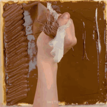 a person frosting a cake with chocolate frosting