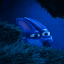 a blue cartoon character with big eyes looks out from behind a tree
